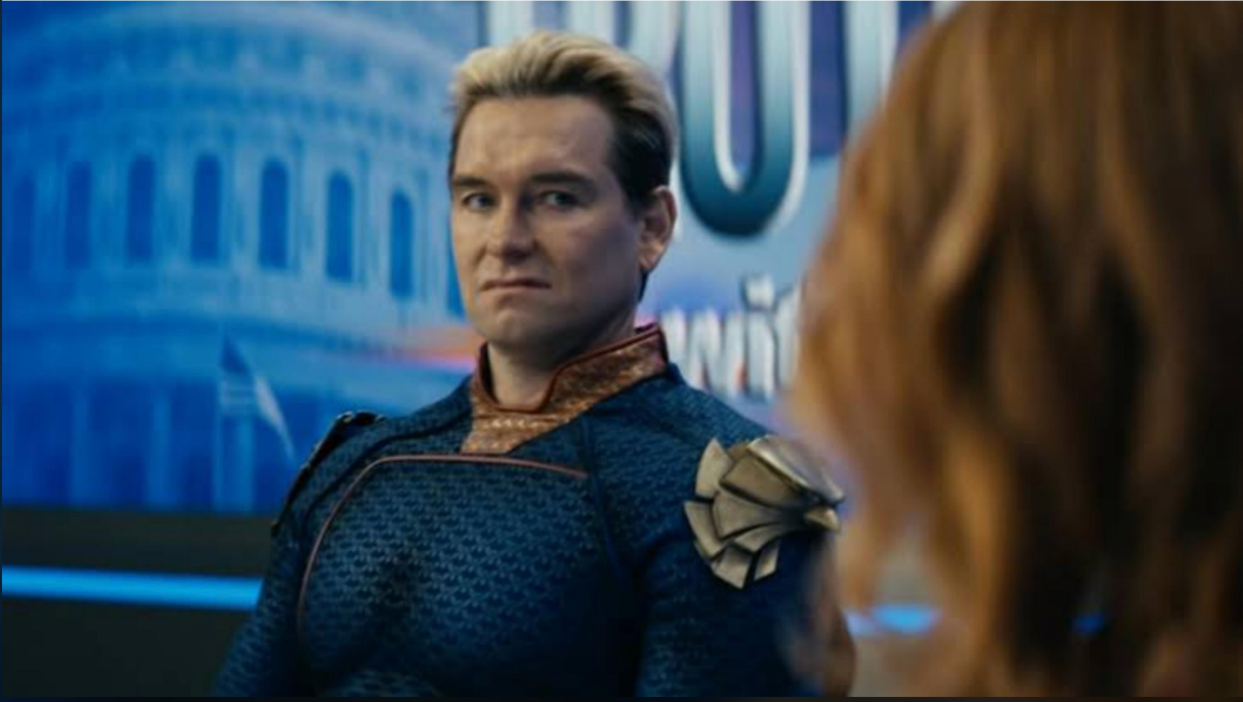 The image features Homelander, a character from the TV series 'The Boys.' He has a tense demeanor, with a slight grimace, conveying a mix of frustration and arrogance. His costume, adorned with a distinctive emblem, showcases his superhero persona, but his expression hints at underlying complexities and moral ambiguity.
The background includes a blue-toned setting that suggests a news studio, which emphasizes the show's satirical take on media and celebrity culture. The presence of the Capitol building silhouette in the background subtly connects to themes of power and authority, integral to the narrative of 'The Boys.' Homelander’s stoic posture contrasts with the chaotic world around him, illustrating the dissonance between his public image and true character. The overall atmosphere is charged with tension, highlighting the show's dark humor and critique of superhero tropes.