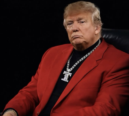 The image depicts Donald Trump, the 45th President of the United States, sitting confidently in a striking red suit paired with a bold black turtleneck, exuding his signature flamboyant style. His demeanor is serious yet self-assured, capturing his unique public persona. The chunky silver chain around his neck adds a touch of glitz, reinforcing his brand image as a larger-than-life character.
The background is dark and minimalistic, drawing all attention to Trump himself, as if he is the centerpiece of a high-stakes performance or a dramatic reveal. The lack of distractions amplifies the intensity of the moment, making it feel like a scene out of a political drama or a celebrity interview. Overall, the image plays on the themes of power and spectacle, showcasing Trump in a manner that blends politics with showmanship.