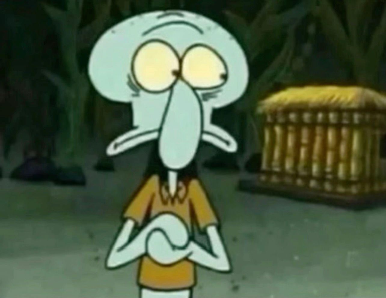 In this scene from the animated series 'SpongeBob SquarePants,' we see Squidward Tentacles, a character known for his cynical outlook and artistic aspirations. His demeanor is one of deep contemplation, with wide eyes suggesting surprise or concern, and his arms crossed defensively. The background is dim and somewhat ominous, hinting at the underwater world of Bikini Bottom, which often serves as a backdrop for Squidward's misadventures. The objects behind him, including a mysterious wooden structure, add an air of intrigue, as they seem to be part of a comedic yet relatable situation typical of the show. The humor lies in Squidward's exaggerated expressions and the absurdity of his surroundings, showcasing the struggles of adult life in a whimsical underwater setting. This scene captures the essence of Squidward's character—always caught between his artistic dreams and the chaos of his life.