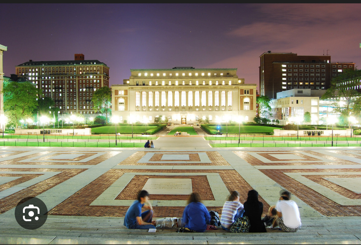 This captivating night scene at Columbia University features four individuals casually seated on the steps of the Low Memorial Library plaza, their backs to the viewer, gazing towards the iconic, brightly illuminated Butler Library. The grand, neoclassical architecture of Butler Library, with its numerous glowing windows, dominates the background, radiating an aura of scholarly intensity. The students appear relaxed and contemplative, perhaps unwinding after a long day of studies or simply enjoying the campus ambiance. The patterned brickwork of the plaza leads the eye directly to the library, firmly establishing the academic context. A humorous touch lies in the potential irony of students sitting outside such a magnificent library, perhaps contemplating their next study session or, more likely, enjoying a well-deserved break from it all.