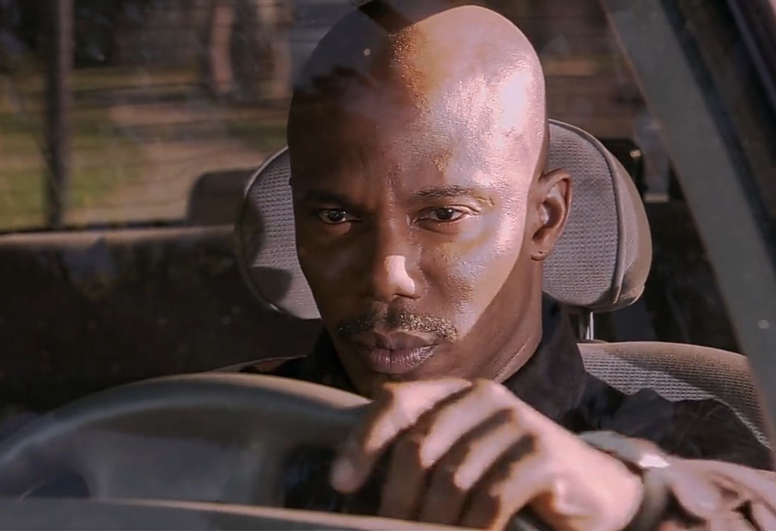This iconic image captures Tyrese Gibson as Jody from the movie "Baby Boy," perfectly embodying the widely recognized "Suspicious Tyrese" meme. Seated in a car, he grips the steering wheel with an expression of intense scrutiny and skepticism. His bald head and face are dramatically lit, highlighting his furrowed brow and narrowed eyes, which convey a profound sense of distrust or contemplation. The blurry background, glimpsed through the car window, hints at movement or an external scene he's intently observing, amplifying the watchful atmosphere. His demeanor is a masterclass in silent judgment, making this shot a universally relatable and humorous visual for anyone questioning a dubious narrative.