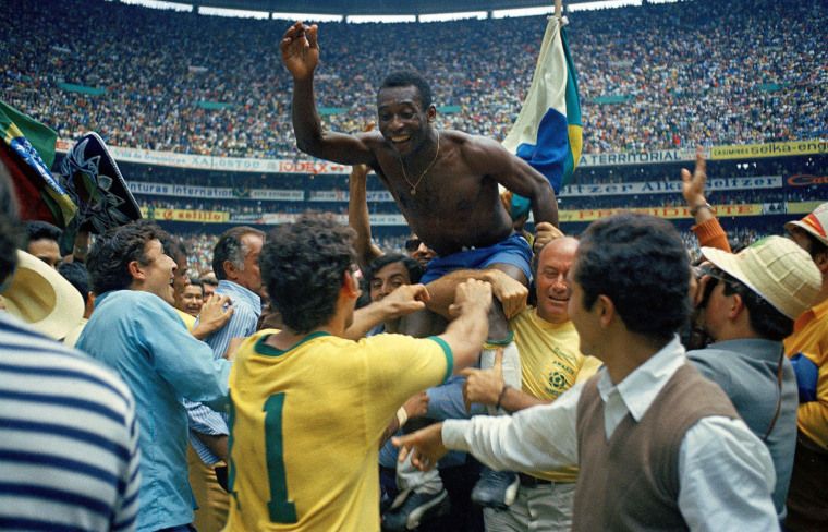 This iconic image captures legendary Brazilian footballer Pelé in a moment of pure, unadulterated triumph, being hoisted aloft by ecstatic fans and teammates after Brazil's victory in the 1970 FIFA World Cup final. His bare chest, blue shorts, and gold chain contrast with the sea of people, as he grins widely, arms raised in joyous celebration. A Brazilian flag waves proudly behind him, symbolizing the nation's glory. The massive, cheering crowd filling the Estadio Azteca in Mexico City forms a vibrant backdrop, underscoring the immense scale and significance of this historic event. The sheer, almost chaotic, joy of the moment, with Pelé looking like a king on a human throne, adds a touch of humorous exuberance to this legendary scene.