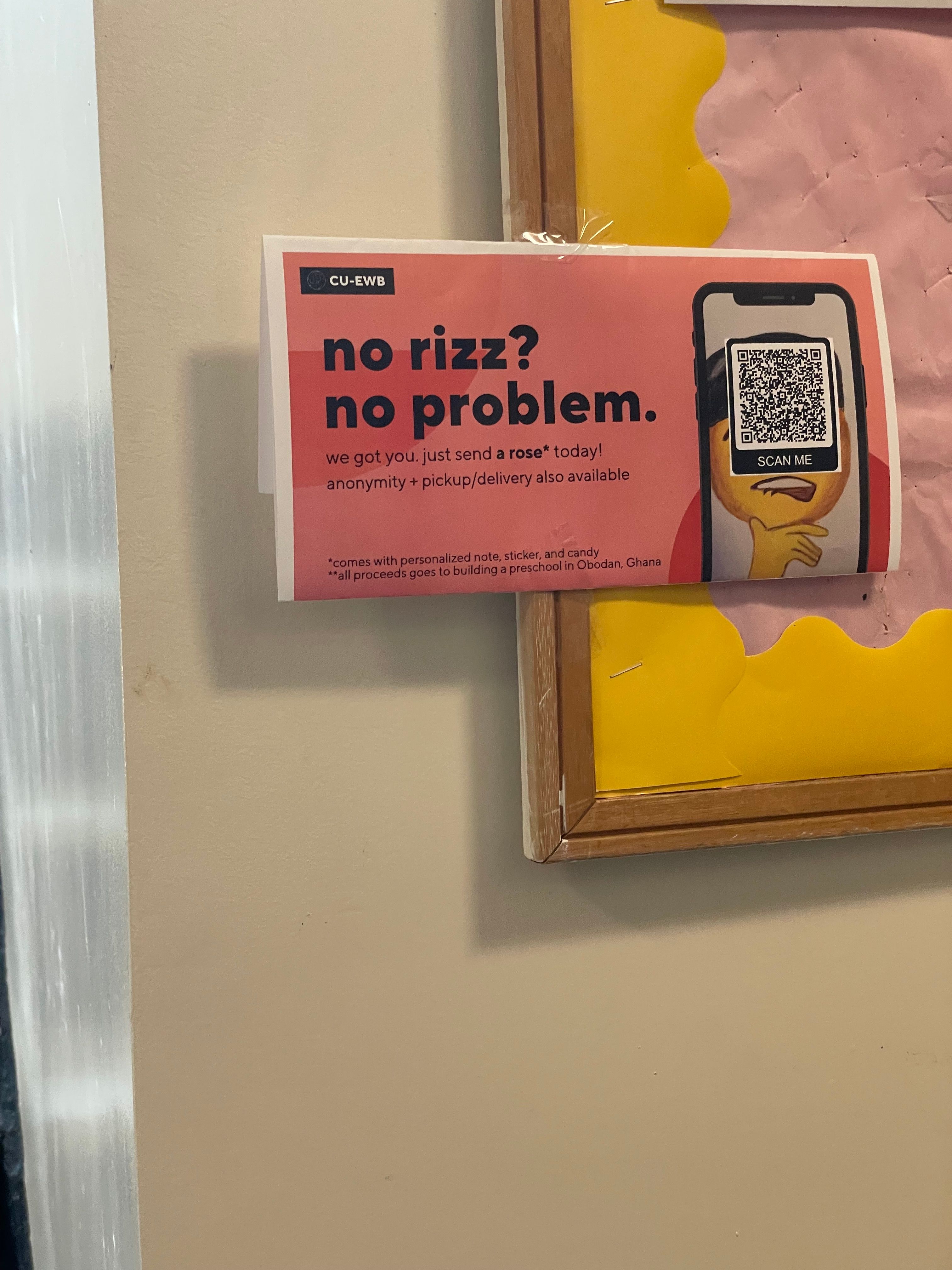 The image features a humorous poster on a beige wall, likely in a school or university setting, given the visible bulletin board with yellow and pink wavy borders. The poster, from 'CU-EWB', boldly declares 'no rizz? no problem.' and offers a solution: 'we got you. just send a rose* today!' complete with anonymity and delivery. A smartphone graphic on the right displays a 'SCAN ME' QR code, with a yellow, slightly bewildered emoji face underneath, perfectly capturing the 'no rizz' predicament. The humor lies in the casual internet slang juxtaposed with a charitable cause: proceeds go to building a preschool in Obodan, Ghana. It's a clever, self-aware fundraiser, probably for Valentine's Day, appealing to students' modern lingo while supporting a noble cause.