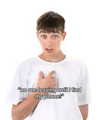This picture captures a young man, likely a teenager, with wide, expressive eyes and a slightly open mouth, conveying a mix of surprise and mild panic. He's wearing a simple white t-shirt against a stark white background, which isolates him and draws full attention to his dramatic expression and the overlaid text. His right hand is pointing towards himself, emphasizing the declaration: "no one leaving until I find my phone!" The humor stems from the universally relatable, yet comically exaggerated, panic of a lost phone, turning a common frustration into a meme-worthy ultimatum. The plain background ensures the focus remains on his relatable, slightly frantic demeanor, making it a perfect template for internet humor.