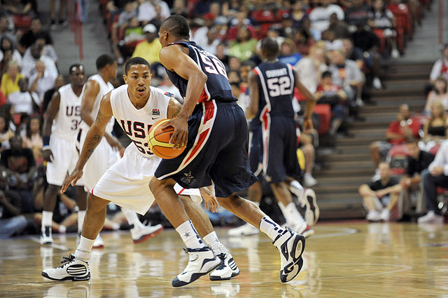 The image captures a dynamic basketball scene with players from the USA Basketball team engaged in a practice session or exhibition game. The player in white, displaying a focused and determined demeanor, is closely guarding an opponent in dark attire, who is skillfully dribbling the ball. The intensity of their expressions suggests a competitive spirit, typical of high-stakes basketball.
In the background, a lively audience can be seen, contributing to the energetic atmosphere of the event. The stands are filled with fans, indicating a significant turnout for this practice or exhibition, which enhances the overall sense of excitement.
The scene embodies the essence of teamwork and athleticism, showcasing the USA Basketball team’s dedication to honing their skills. Overall, it’s a vibrant snapshot of sportsmanship and the thrill of basketball, making it an engaging moment for both players and spectators alike.