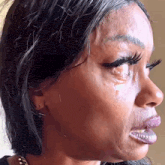 This close-up image captures a woman in profile, her face contorted in an expression of intense emotion, likely profound sadness or distress. A tear visibly streams from her eye, which is adorned with dramatically long eyelashes, while her mouth is slightly open as if mid-sob or gasp. Her dark hair frames her face, and the background is a soft, out-of-focus light-colored wall, offering no specific contextual clues beyond a simple indoor setting. The raw, unfiltered emotion displayed makes this image highly recognizable as a popular internet meme, often used humorously to convey extreme reactions or 'ugly crying' in various relatable situations, highlighting the universal experience of overwhelming feelings.