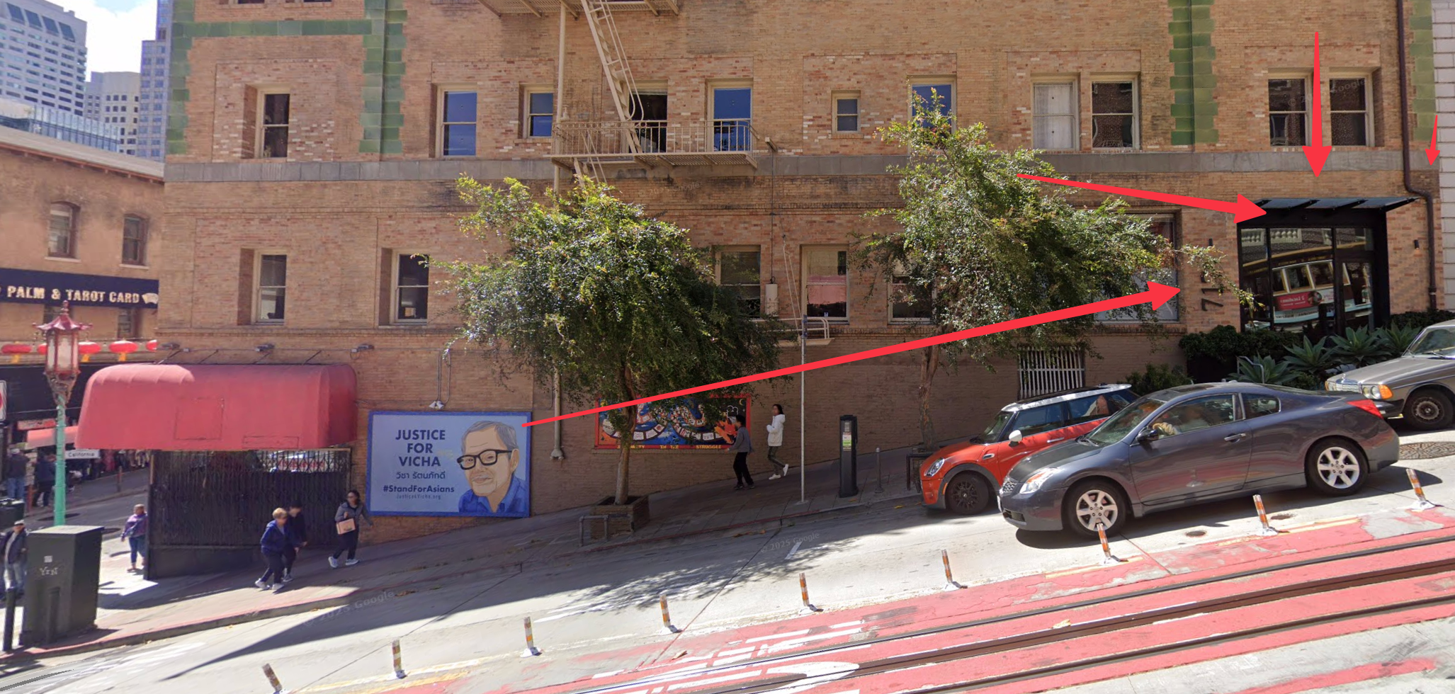 This vibrant street scene captures a slice of urban life, likely San Francisco, given the iconic cable car tracks and steep incline. Dominating the foreground is a poignant blue banner advocating 'JUSTICE FOR VICHA' with a gentle portrait of an older man, his demeanor calm yet impactful, urging viewers to '#StandForAsians.' This powerful message is set against a backdrop of historic brick buildings, some adorned with green tiles, and a bustling sidewalk where pedestrians casually stroll. Two leafy trees stand like silent sentinels, perhaps whispering about the city's daily dramas. In the reflection of a modern glass storefront, a classic cable car seems to be playfully peeking out. The juxtaposition of everyday city life with a call for social justice creates a compelling narrative, highlighting the ongoing struggle for equity within a dynamic community, possibly Chinatown, hinted at by nearby cultural elements.