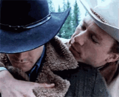 The image captures a poignant moment from the movie "Brokeback Mountain," featuring the characters Ennis Del Mar and Jack Twist. Their demeanor is characterized by a mix of longing and vulnerability, with Ennis appearing somewhat withdrawn, his face partially obscured by his hat, suggesting an internal struggle. Jack, on the other hand, leans in closer, conveying an intensity and yearning for connection.
The backdrop consists of a rugged, natural landscape, indicative of the film's themes of love and isolation. This setting enhances the emotional weight of their relationship, symbolizing both freedom and confinement. The film is renowned for its exploration of complex relationships against the backdrop of societal expectations, making this scene particularly impactful.
Overall, the image encapsulates a moment of intimacy that is both tender and fraught with tension, highlighting the characters' deep connection amidst the challenges they face.