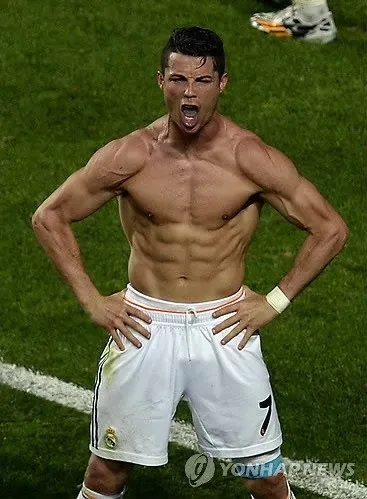 The image features Cristiano Ronaldo, the renowned Portuguese footballer, showcasing his intense emotion during a football match. His powerful stance, hands on his hips, and the fierce expression on his face suggest a moment of triumph, likely celebrating a goal. Ronaldo's toned physique, highlighted by his bare upper body, illustrates his dedication to fitness and the sport. The backdrop, presumably a vibrant stadium filled with cheering fans, adds to the excitement of the scene, capturing the electric atmosphere of a pivotal match. The overall context reflects Ronaldo's legendary status in football, embodying his passion and competitiveness. The humor in the image might lie in the dramatic pose, reminiscent of a superhero ready to save the day, or a scene where he's playfully challenging the audience to keep up with his athletic prowess.